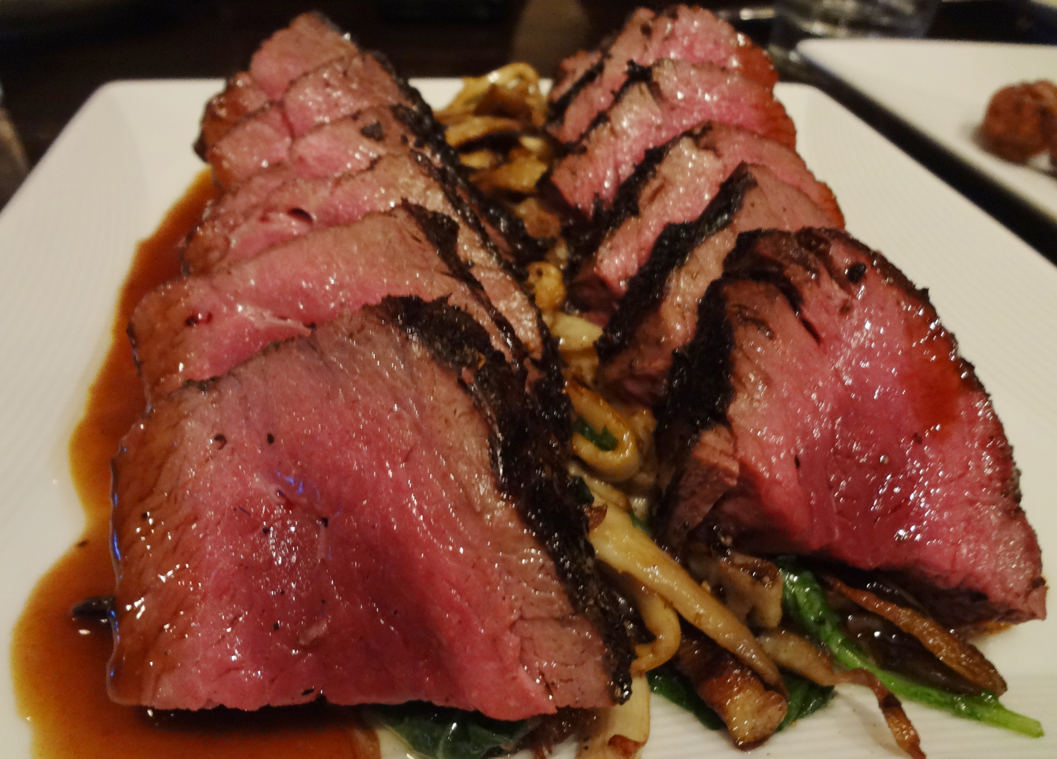 Rare ostrich fan filet on a bed of pan roasted mushrooms
